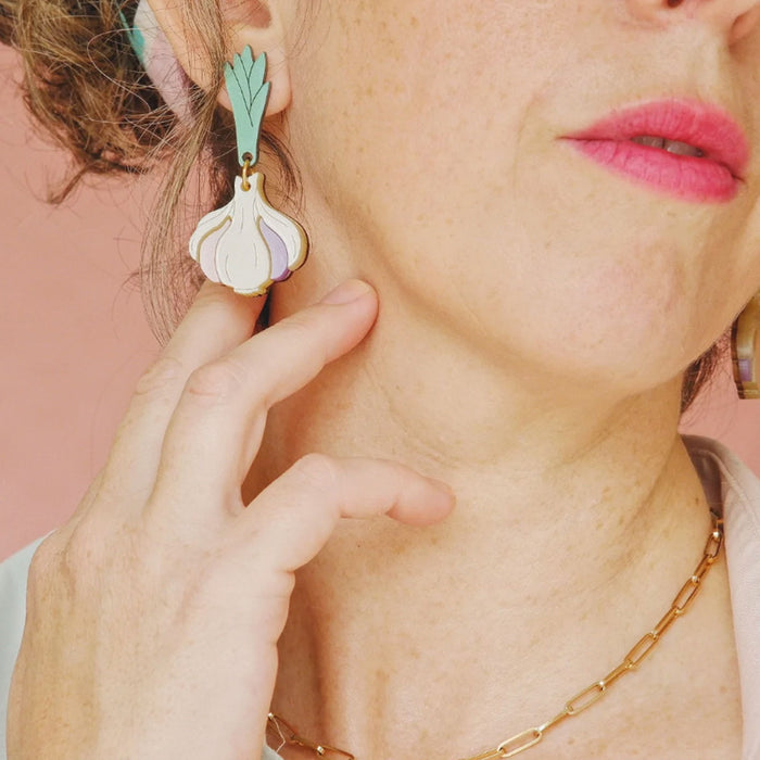 Modelo con pendientes de metacrilato en tonos marfil, malva, rosa palo, verde y dorado en forma de cabeza de ajos.