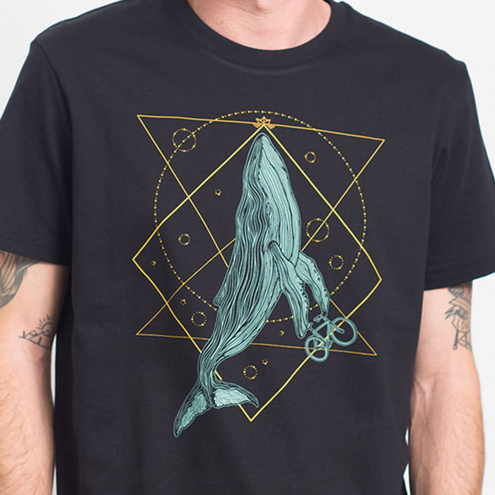 Camiseta negra con ilustración de ballena con bicicleta en tonos azules junto con una geometría decorativa en amarillos.