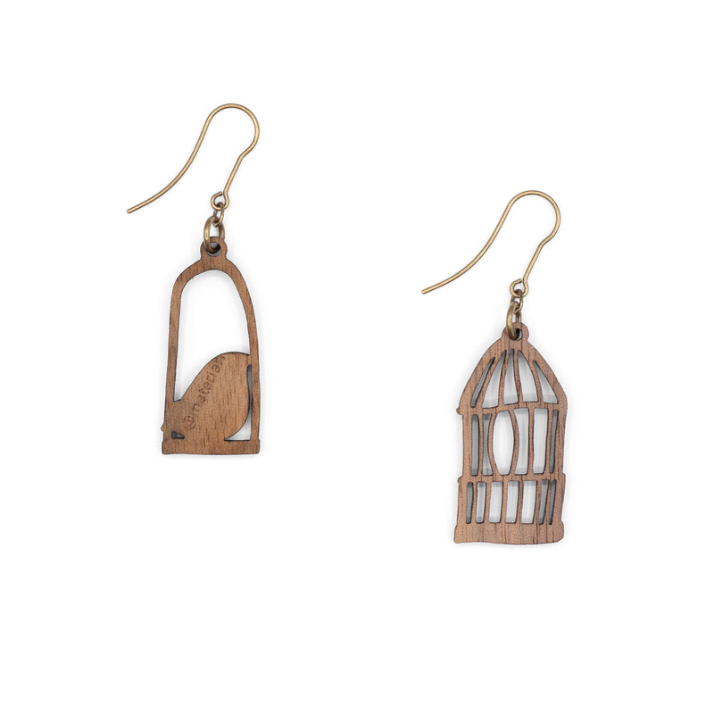 parte trasera de Pendientes desparejados en forma de pájaro azul en un columpio y jaula de pájaro sobre fondo blanco.