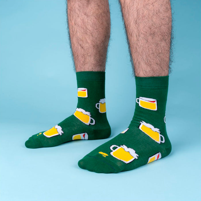 Fotografía de pies de hombre con calcetines verdes con estampado de cervezas en fondo azul