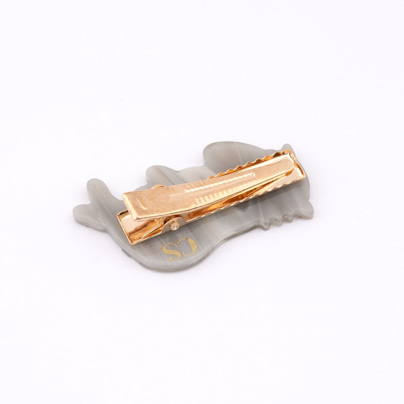 Pinza para el pelo en forma de gato gris lamiéndose una pata. Pinza para el pelo en forma de gato aseándose, divertida y original. Fabricada con acetato de celulosa reciclado. Vista sobre mano. Vista trasera de la pinza.