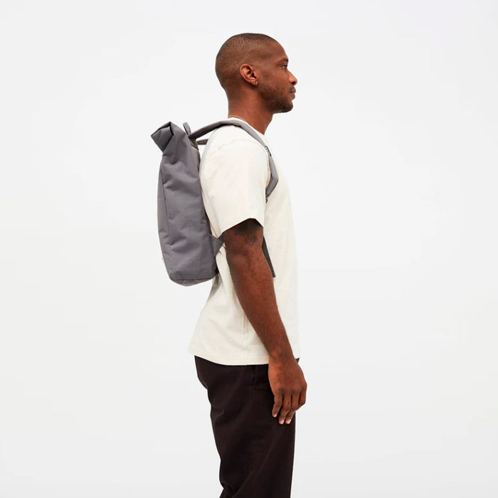 Mochila grande gris minimalista de cierre enrollable enrollada vista de perfil con modelo