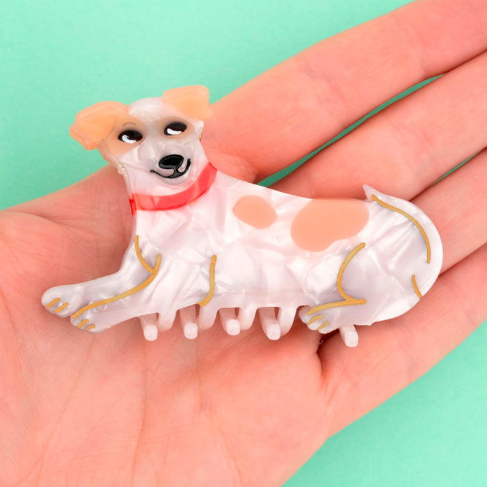 Pinza para el pelo de acetato de celulosa en tonos blancos y marrones con acabado carey en forma de perro jack russel tumbado con collar rojo.