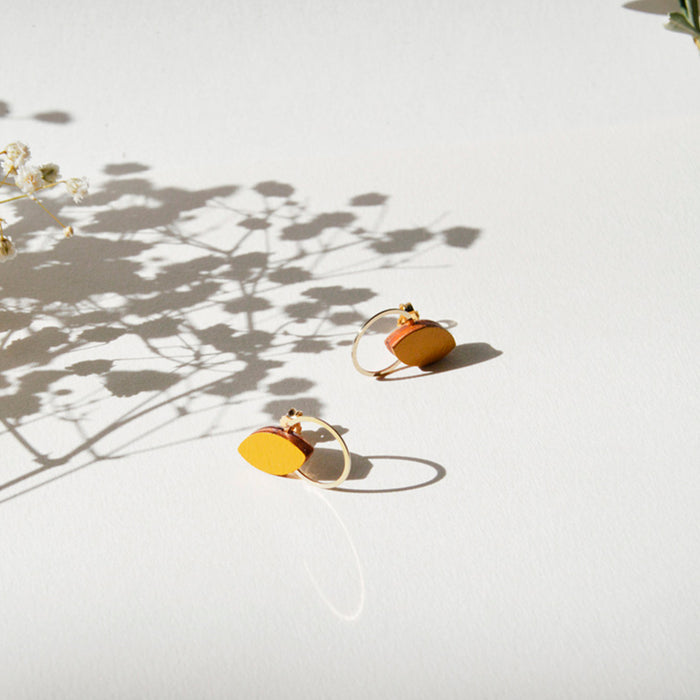 Pendientes de madera con forma de hoja de olivo en color mostaza y aro plano dorado en la parte inferior.