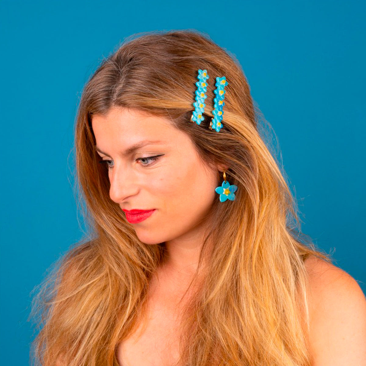 Pasador de pelo en forma de fila de flores nomeolvides azules con detalles en blanco y amarillo. Fabricado en acetato de celulosa reciclado. Foto en modelo rubia.