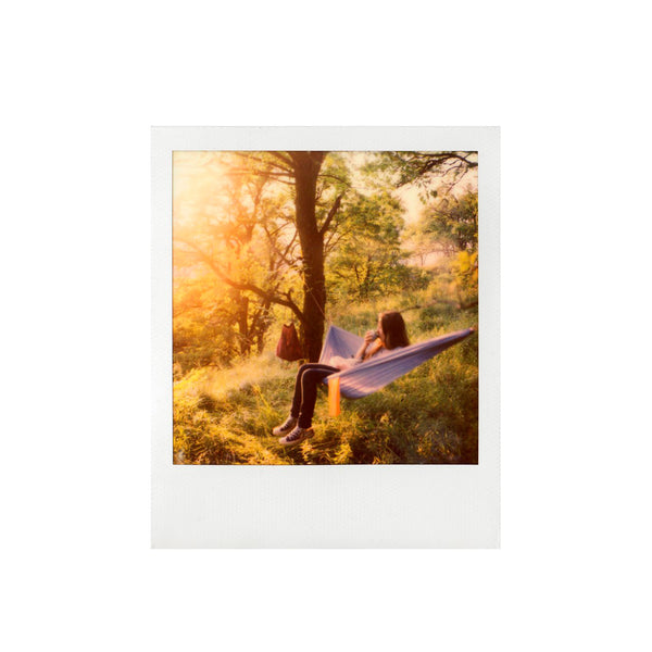 Fotografía polaroid sx-70 a color de mujer tumbada en una hamaca en un fondo boscoso
