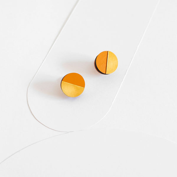Pendientes de botón redondos, medio círculo de madera pintada de color mostaza y medio círculo de latón dorado.