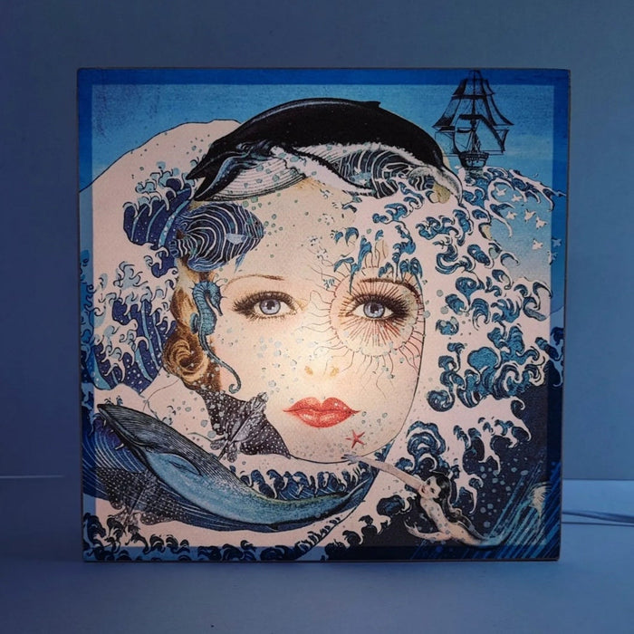 Caja de luz de madera y papel con la imagen de un rostro femenino rodeado de olas y animales marinos. Caja de luz hecha de forma manual con imagen de olas, ballenas, peces y mujer vintage.