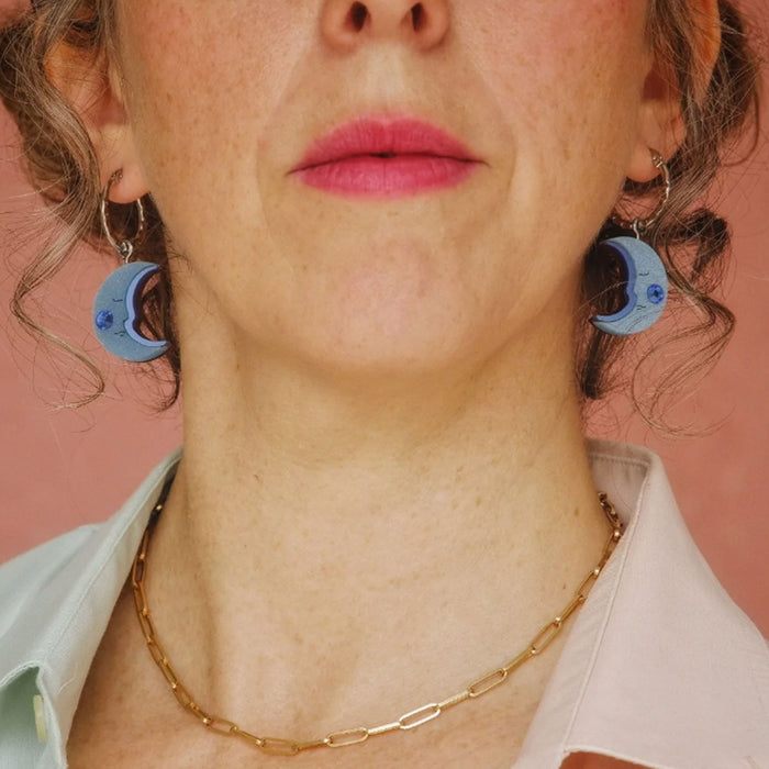 Modelo de frente con Pendientes de aro plateado con charm en forma de media luna azul con mejillas de cristal de swarovski