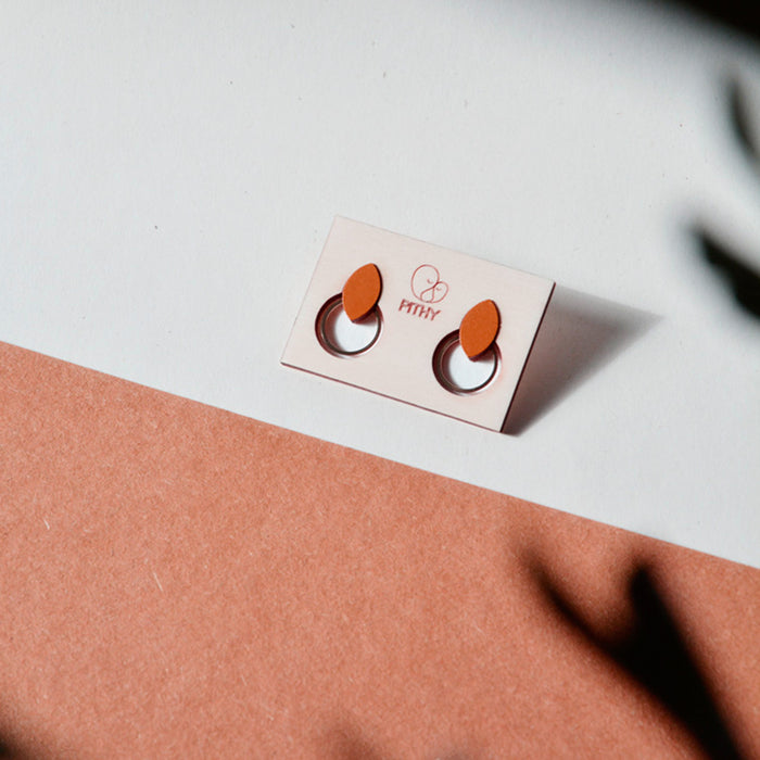 Pendientes de madera con forma de hoja de olivo en color terracota y aro plano dorado en la parte inferior.