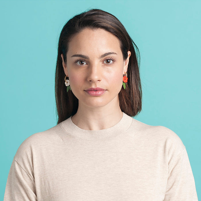 Modelo con Pendientes de aro con charm de madera en forma de rosa roja, blanca y hojas verdes.