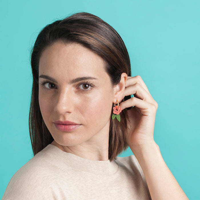 Modelo con Pendientes de aro con charm de madera en forma de rosa roja y hojas verdes.