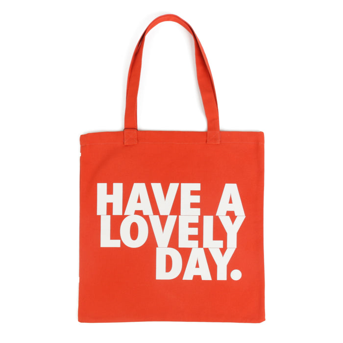 Tote bag color naranja con serigrafía frase “Have a lovely day.” en mayúsculas en tipografía tipo sans serif en color blanco.