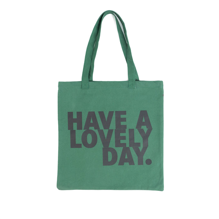 Tote bag color verde con serigrafía frase “Have a lovely day.” en mayúsculas en tipografía tipo sans serif en color negro.