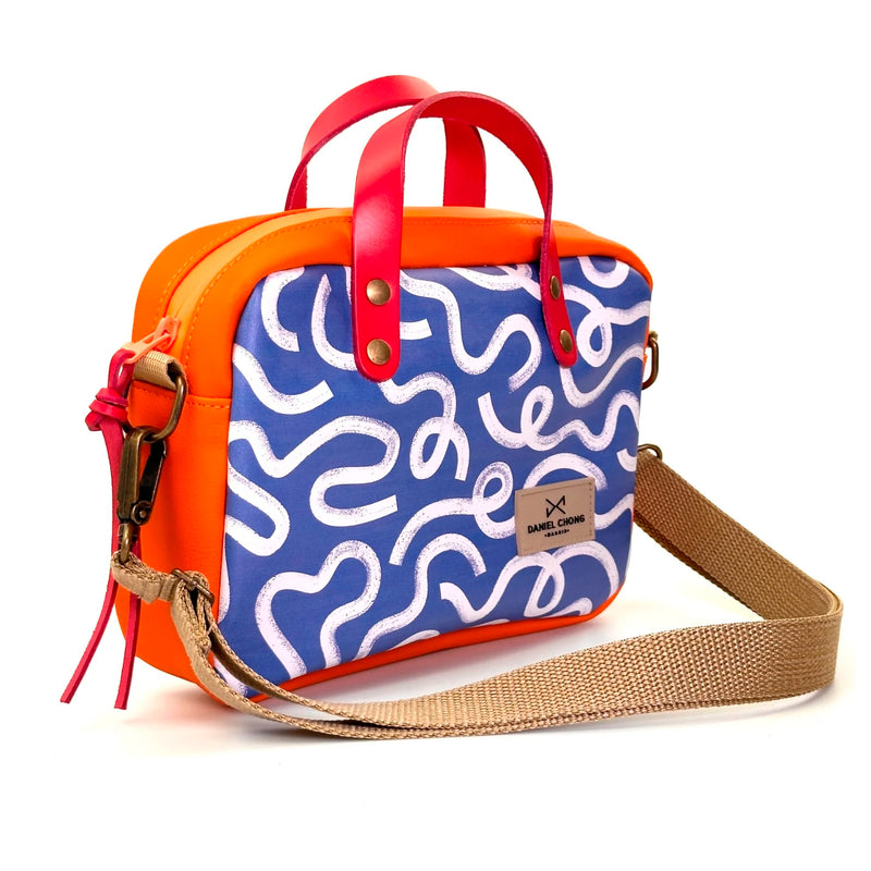 Bandolera Urban Box con asas impermeable Daniel Chong - Vueltas y naranja