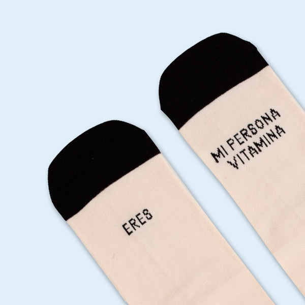 Detalle de calcetines blancos con rallas de colores y puntera negra con la frase "Eres mi persona vitamina".