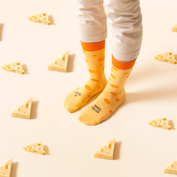 Calcetines amarillos que imitan un queso gruyere con la frase "estas como un queso".