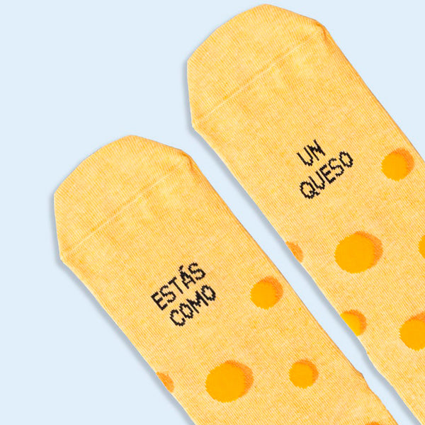 Detalle de Calcetines amarillos que imitan un queso gruyere con la frase "estas como un queso".