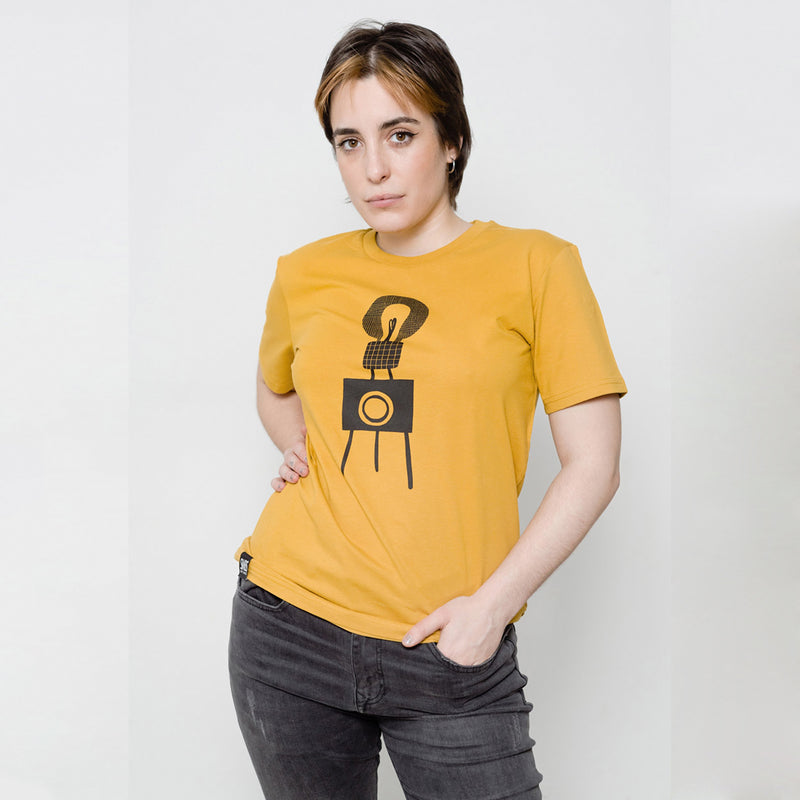Camiseta de algodón color mostaza con ilustración.   Camiseta mostaza con ilustración de cámara vintage en tonos negros. 