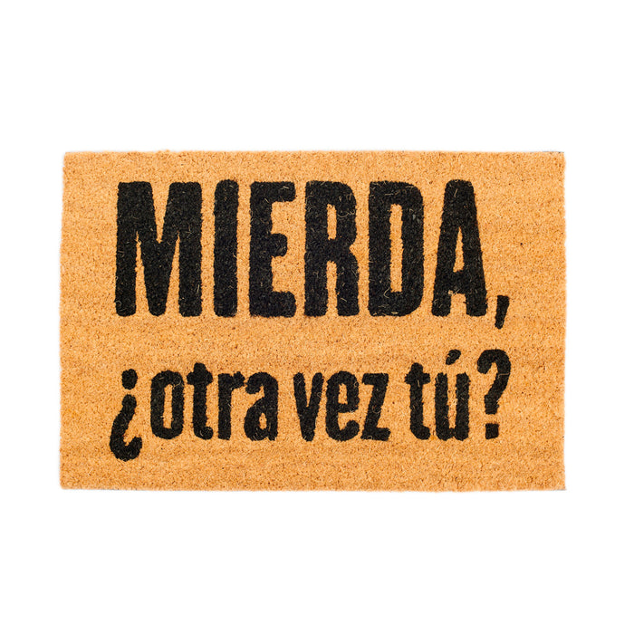 Felpudo con mensaje “Mierda ¿otra vez tú?”. Felpudo de hebras de coco natural en color marrón claro y mensaje con letras negras.