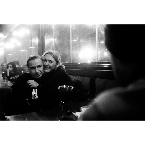 Fotografía en blanco y negro de dos personas abrazándose en el interior de un bar tomada con la película Ilford HP5 Plus ISO 400.