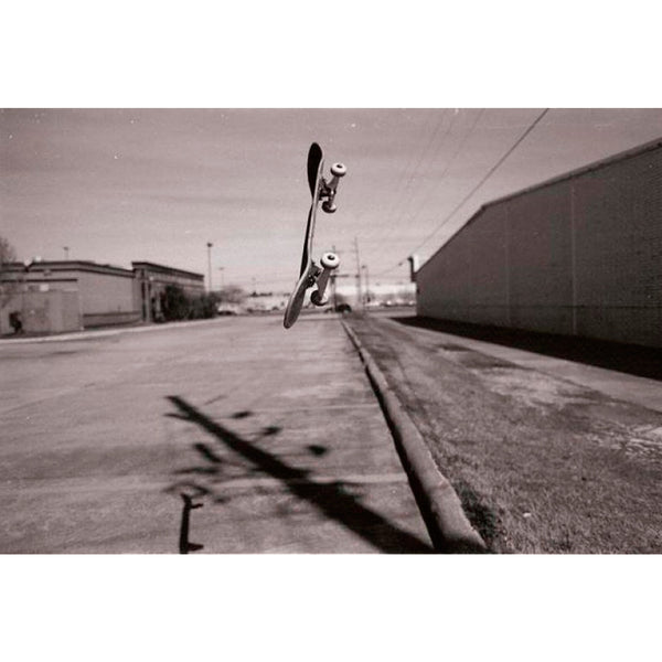 Fotografía en blanco y negro de patinete en el aire y fondo urbano tomada con la película fotográfica Kodak TMAX 400
