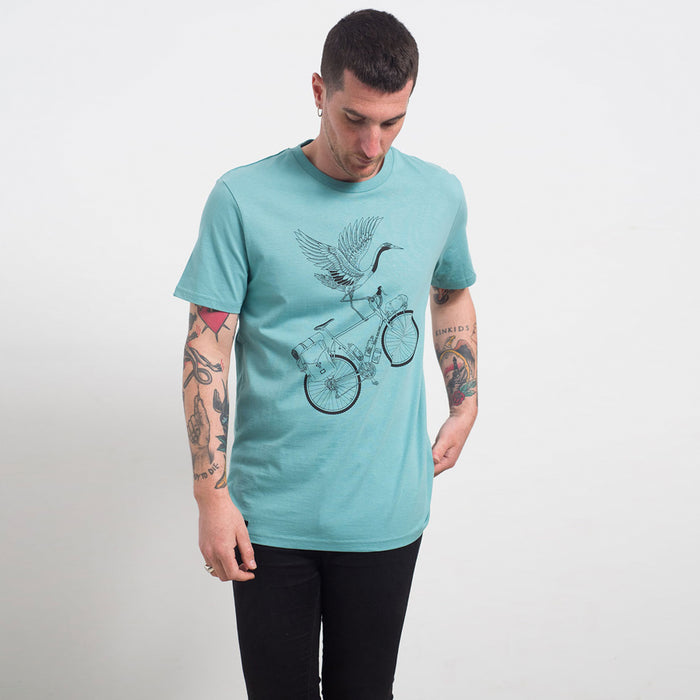 Camiseta azul claro con ilustración de grulla sobre una bicicleta con equipaje a línea negra. Camiseta de manga corta de talle medio impresa mediante serigrafía a una tinta. Camiseta ideal para los amantes de los viajes