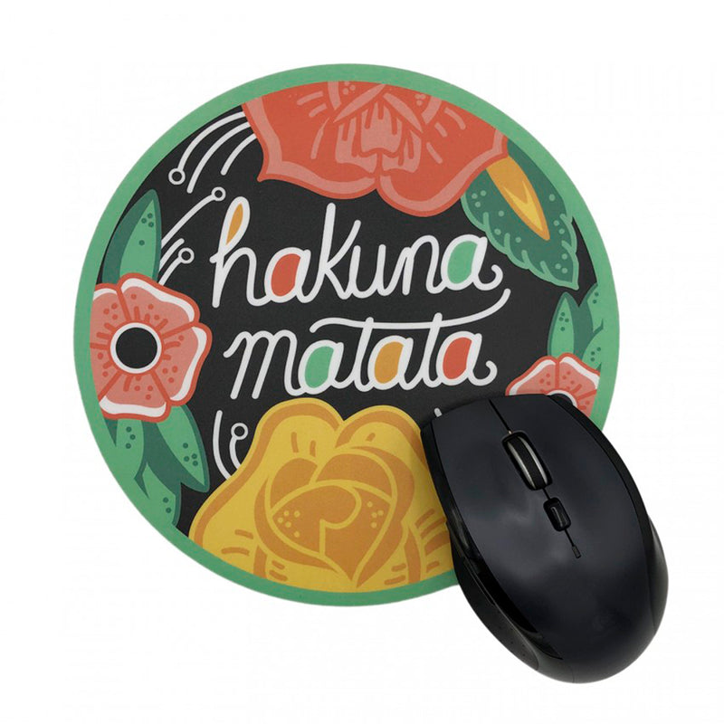 Alfombrilla de ratón redonda con fondo negro, borde verde y dibujo de flores y hojas y el texto "Hakuna Matata". Alfombrilla para ratón inspirada en El Rey León.