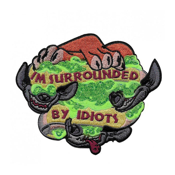 Parche termoadhesivo bordado con la frase "I'm surrounded by idiots" unas patas de león y las mandíbulas de tres hienas en un fondo de humo verde.