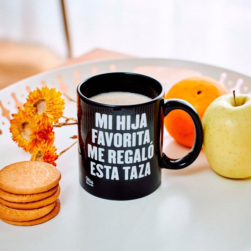 Taza de cerámica negra con frase "Mi hija favorita me regaló esta taza" en letras blancas.