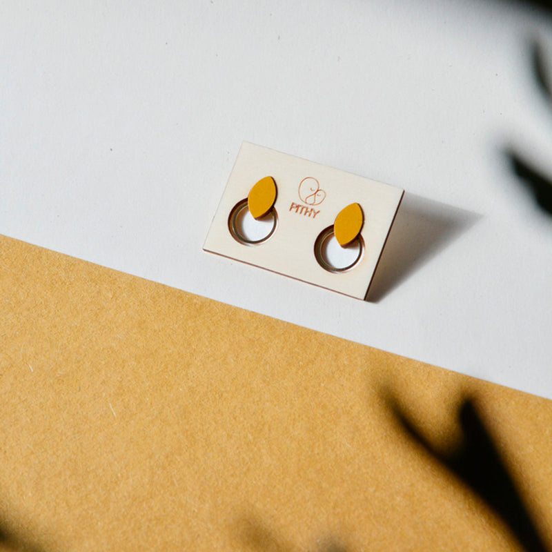 Pendientes de madera con forma de hoja de olivo en color mostaza  y aro plano dorado en la parte inferior.