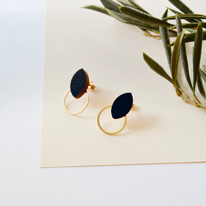 Pendientes de madera con forma de hoja de olivo en color negro  y aro plano dorado en la parte inferior.
