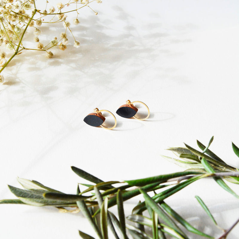 Pendientes de madera con forma de hoja de olivo en color negro  y aro plano dorado en la parte inferior.