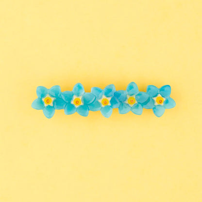 Pasador de pelo en forma de fila de flores nomeolvides azules con detalles en blanco y amarillo. Fabricado en acetato de celulosa reciclado.