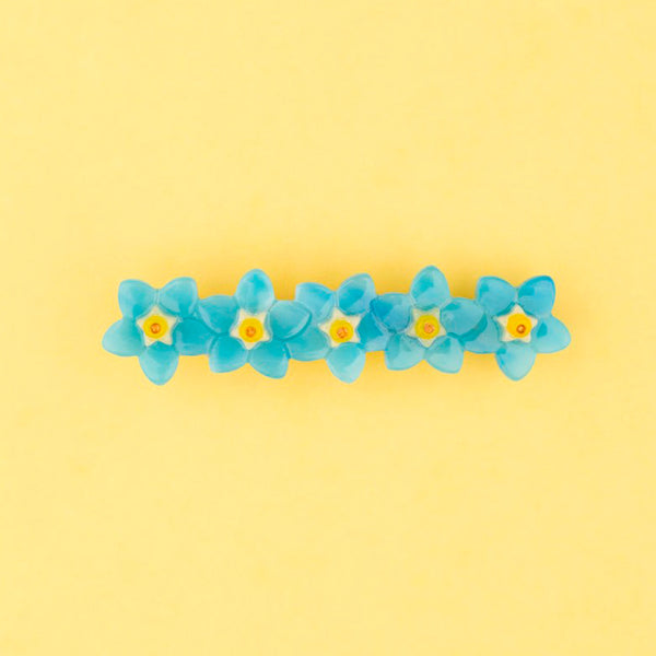 Pasador de pelo en forma de fila de flores nomeolvides azules con detalles en blanco y amarillo. Fabricado en acetato de celulosa reciclado.