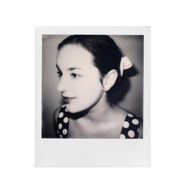 Fotografia polaroid 600 en blanco y negro de primer plano de perfil de mujer con pelo negro y vestido de lunares