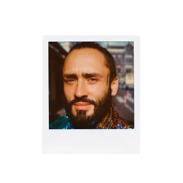 Fotografía polaroid a color sx-70 de hombre con barba y ojos claros en primerísimo primer plano