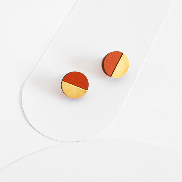 Pendientes de botón redondos, medio círculo de madera pintada de color terracota y medio círculo de latón dorado.