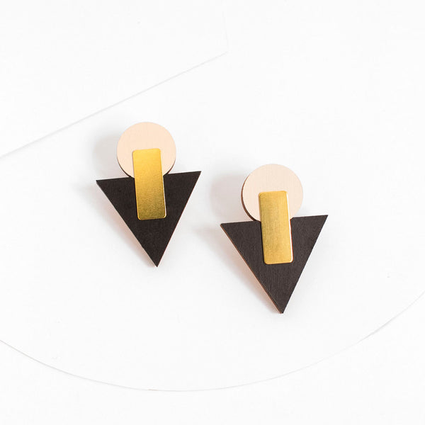 Pendientes de madera con un círculo beige y un triángulo negro con una pieza de latón dorado rectangular que une las dos formas por la parte delantera.
