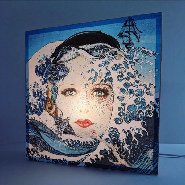 Caja de luz de madera y papel con la imagen de un rostro femenino rodeado de olas y animales marinos. Caja de luz hecha de forma manual con imagen de olas, ballenas, peces y mujer vintage.