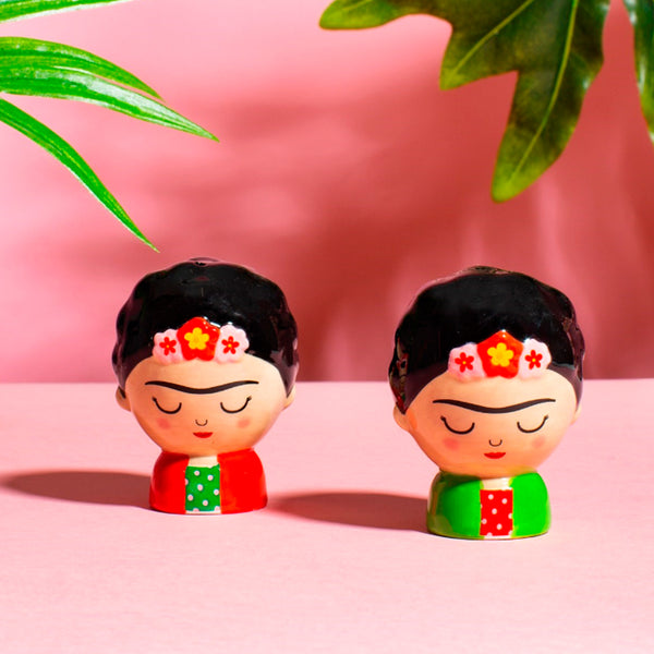 Salero y pimentero en forma de dos pequeñas Frida Kahlo. Salero y  pimentero Frida Kahlo con vestido rojo y verde con lunares y vestido verde y rojo con lunares.