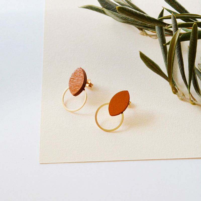 Pendientes de madera con forma de hoja de olivo en color terracota  y aro plano dorado en la parte inferior.