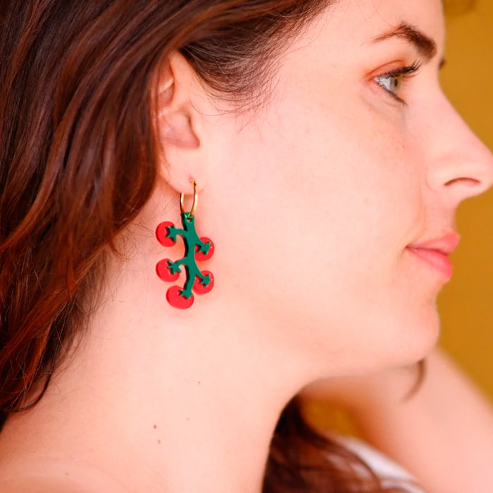 Modelo con pendientes de metacrilato en forma de ramillete de tomates.