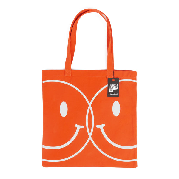 Tote bag color naranja con serigrafía de dos caritas sonrientes tipo smiley en color blanco en una cara.