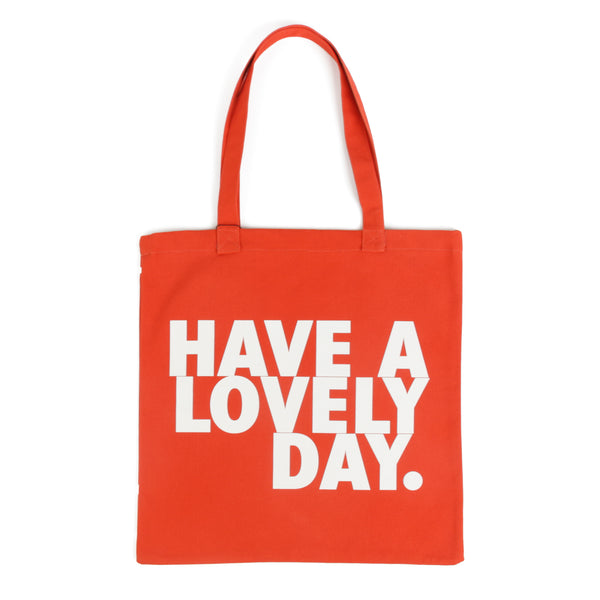  Tote bag color naranja con serigrafía frase “Have a lovely day.” en mayúsculas en tipografía tipo sans serif en color blanco.