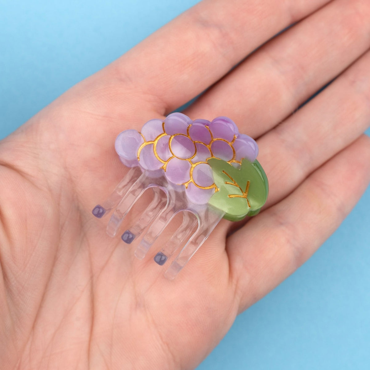 Pinza mini para el pelo en forma de racimo de uvas. Pinza original y divertida fabricada con acetato de celulosa reciclado y biodegradable. Visa sobre mano.